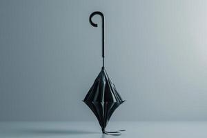 Black umbrella standing upright on a smooth surface against a pale background in a minimalist setting photo