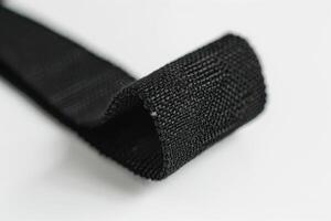 Close-up of a black textile strap with textured surface against a light background photo