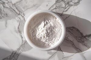 White powder in a round container placed on a marble surface with natural light illuminating the scene photo