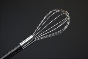 Close-up of a stainless steel whisk against a dark background showcasing its sleek design and functionality in cooking photo