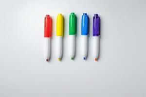 Colorful markers arranged in a row on a plain white background photo
