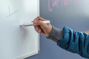 Person writing on a whiteboard during a classroom session photo
