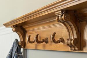 Wooden wall-mounted coat rack with multiple hooks and decorative molding in a modern hallway photo