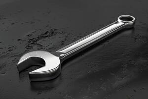 A shiny stainless steel wrench resting on a dark surface in a well-lit workshop photo