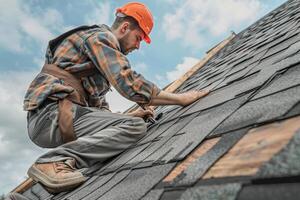 Skilled worker installing shingles on a roof under a partly cloudy sky in the afternoon photo