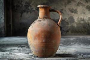 Ancient terracotta jug resting on a stone surface in a rustic setting with muted colors photo