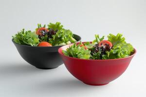 Green salads with tomatoes in contrasting bowls, served in a minimalist setting photo