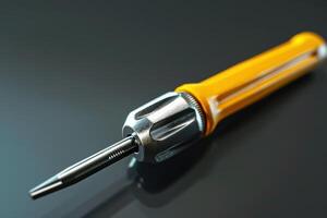 Close-up of a yellow-handled screwdriver resting on a glossy black surface photo