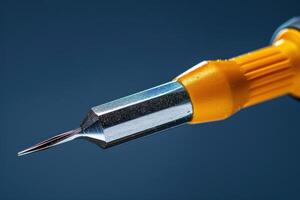 Close-up of a precision screwdriver against a blue background showcasing fine details photo