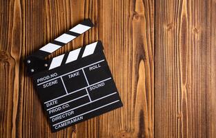 black movie clapper with white inscriptions on a wooden table photo