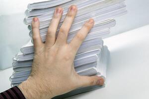 man's hand holds one notebook from a stack of notebooks concept photo