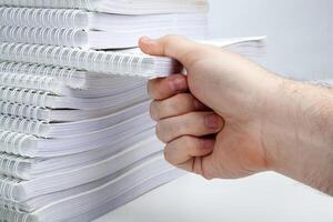 man's hand takes one notebook from a stack of notebooks concept photo
