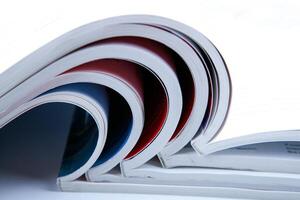 stack of open glossy magazines on white background photo