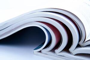 stack of open glossy magazines on white background photo