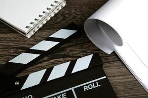 black movie clapper with script sheets and notebook on a wooden table photo