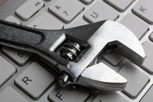 adjustable wrench and a computer keyboard close up photo