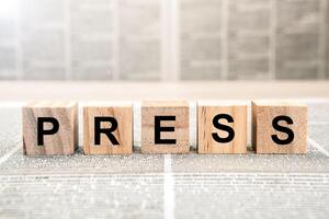 Five wooden cube blocks with the text press on a newspaper background photo
