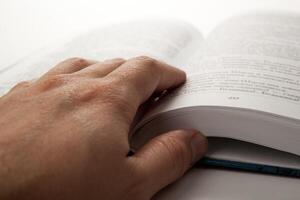 man's hand on an open book with white pages photo