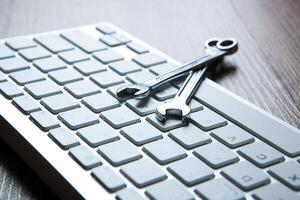 two wrenches and a computer keyboard close up photo
