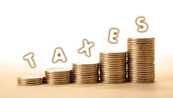stacks of coins on a white background with inscription taxes photo