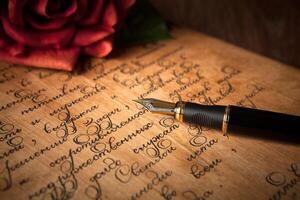 fountain pen on letter with text and red rose on a table photo