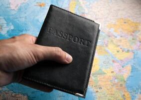 passport of a citizen in the hand of a person on the background of a map of the world photo