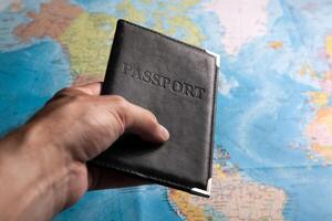 passport of a citizen in the hand of a person on the background of a map of the world photo