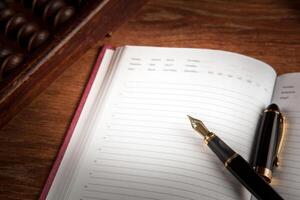 fountain pen and diary on a table with an abacus photo