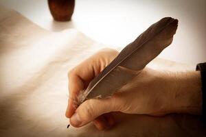 writer holds a fountain pen over writing paper and a signature photo