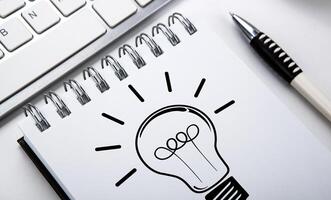 business still life of a notebook with an icon of idea and keyboard on the desktop photo
