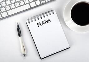 business still life of a notebook with an inscription plans and keyboard on the desktop photo