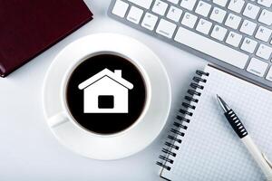 symbol of the house and a cup of coffee with keyboard and diary photo
