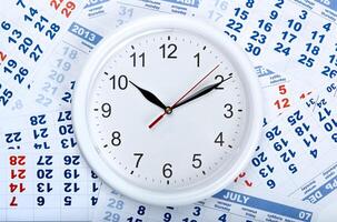 clock with wall calendar sheets with the number of days photo