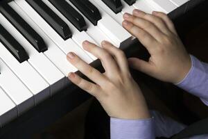 hands of a little boy on the piano keys photo