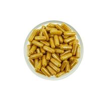 Top view of a group of turmeric herbal capsules in a small glass bowl on a white background. photo