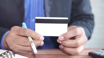 A man holding a credit card in front of a notebook video