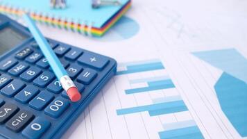 A blue calculator, pen and a paper with graphs video