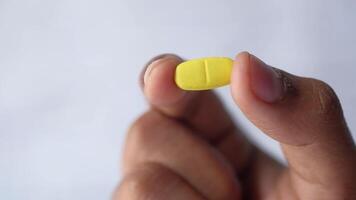 A person holding a yellow pill in their hand video