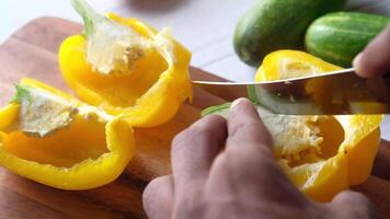 A person cutting up yellow peppers with a knife video