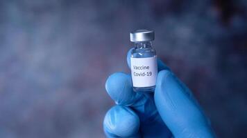 A person holding a small bottle with a vaccine video