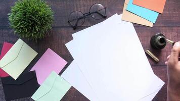 A person's hand writing on a piece of paper with a pen and a pen on a desk video
