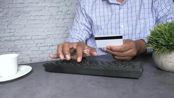 A man is typing on a keyboard and holding a credit card video