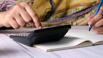 A person is using a calculator to calculate the amount of money video