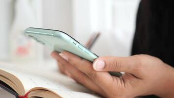 A Person is Utilizing a Smartphone While Taking Detailed Notes in a Notebook for Efficiency video
