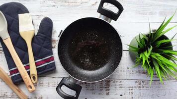 An Overhead Perspective of Cooking Utensils Including a Wok and a Green Plant on a Rustic Table video