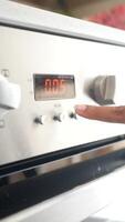 A hand is using a finger to activate the timer button on the control panel of a stainless steel oven video