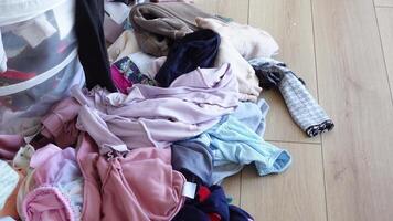 A Chaotic and Messy Pile of Various Colorful Clothes Scattered on a WellWorn Wooden Floor Surface video