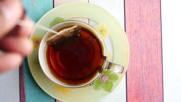 A steaming cup of tea placed alongside a tea bag on a vibrant and colorful table setting video