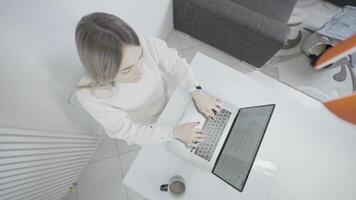 A woman is seated at a desk using a laptop computer video