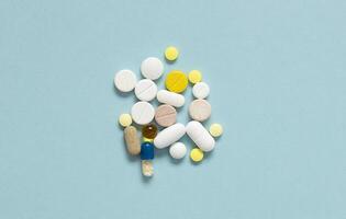 A lot of multicolored pills and capsules on blue background. Concept to keep immunity on a high level.. photo